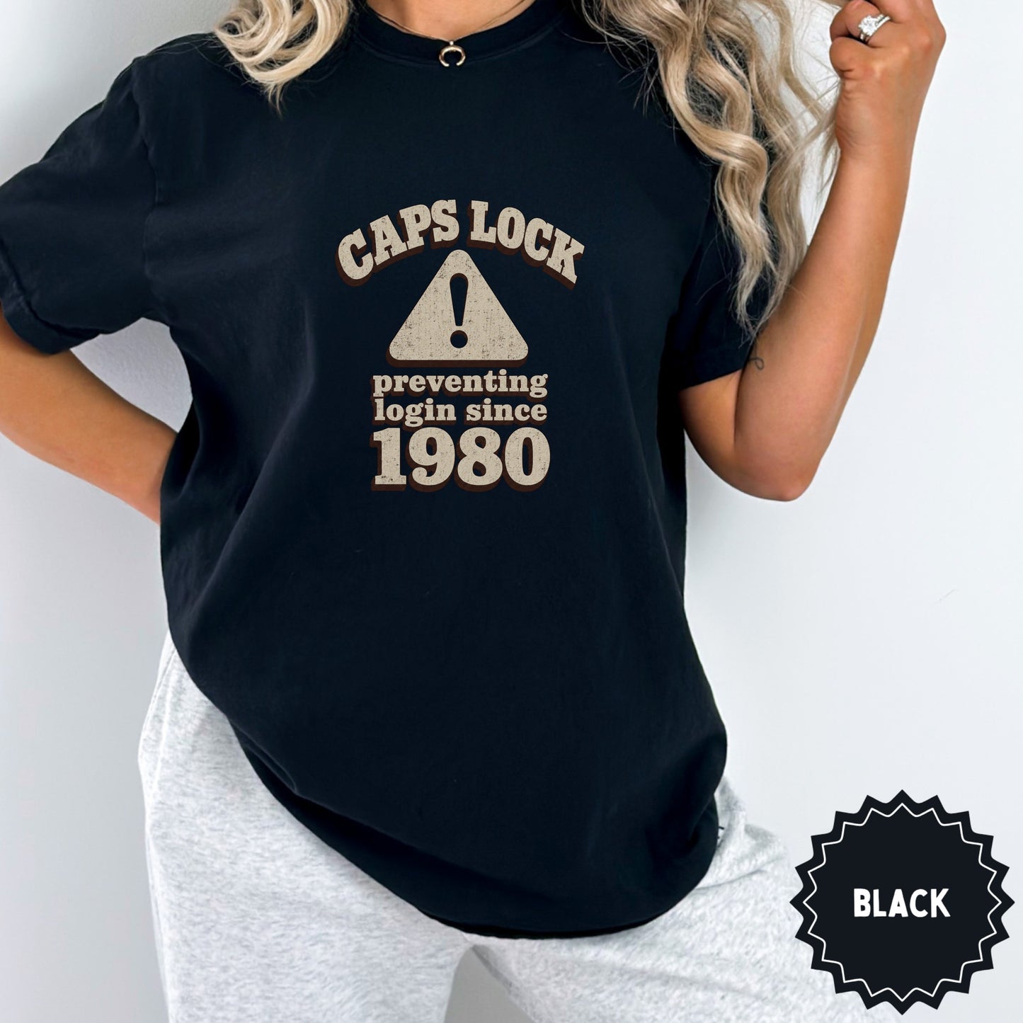Black t-shirt with "Caps Lock Preventing Login Since 1980" text and warning symbol.