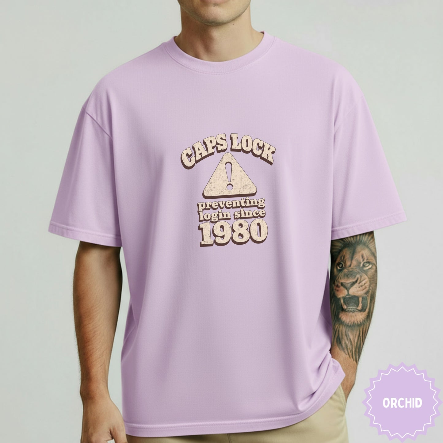 Lavender t-shirt with "Caps Lock preventing login since 1980" text and triangle warning sign.