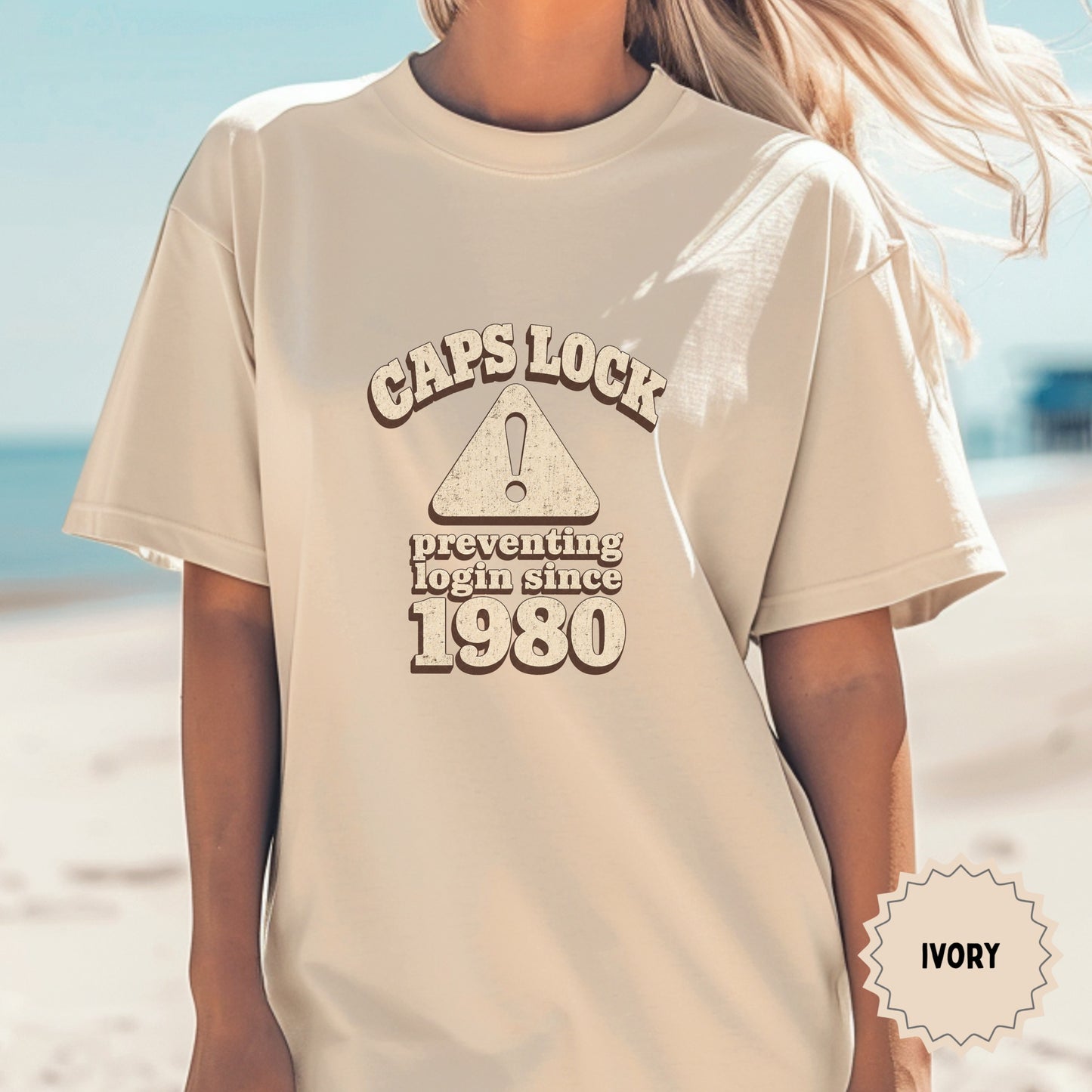 Cream t-shirt with "Caps Lock Preventing Login Since 1980" text and caution triangle.