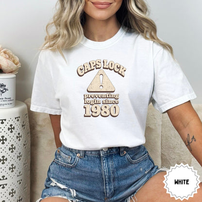 White t-shirt with "CAPS LOCK preventing login since 1980" text and warning symbol.
